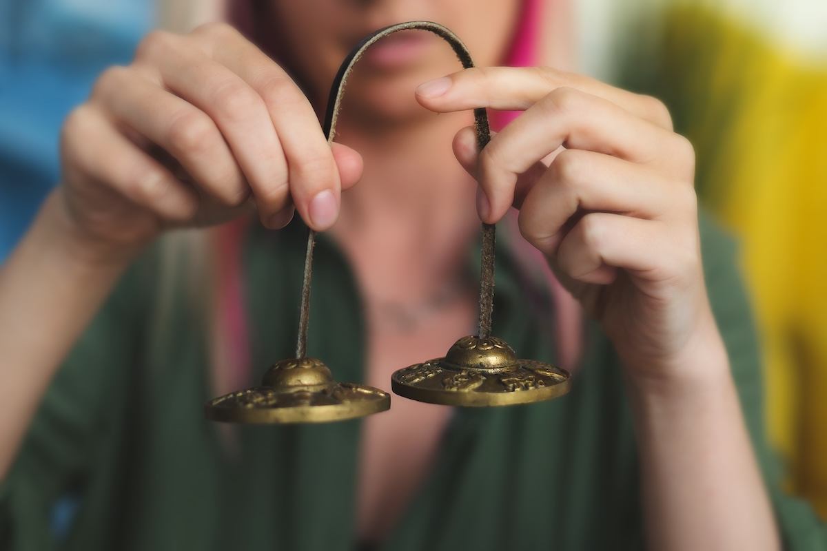 Practitioner using tingsha bells as part of a sound therapy spa treatment