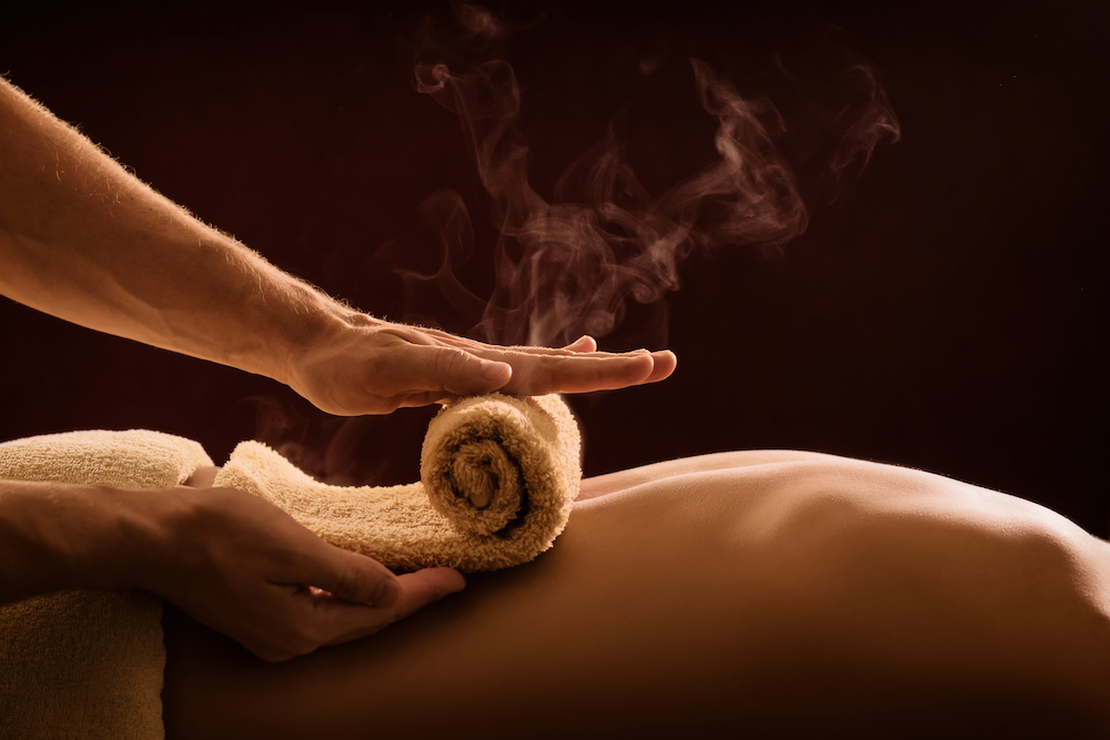a hot towel being rolled on a person's back ahead of a massage