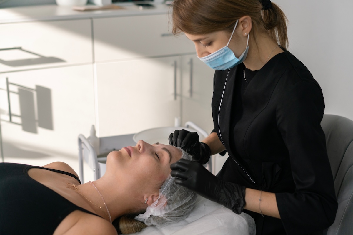 Beauty therapist carefully placing a hair cap on a client in a modern salon, creating a calm and relaxing experience