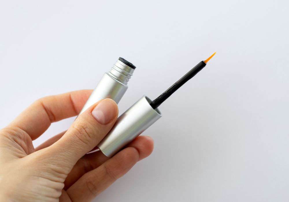 An open tube of lash serum in plain silver packaging