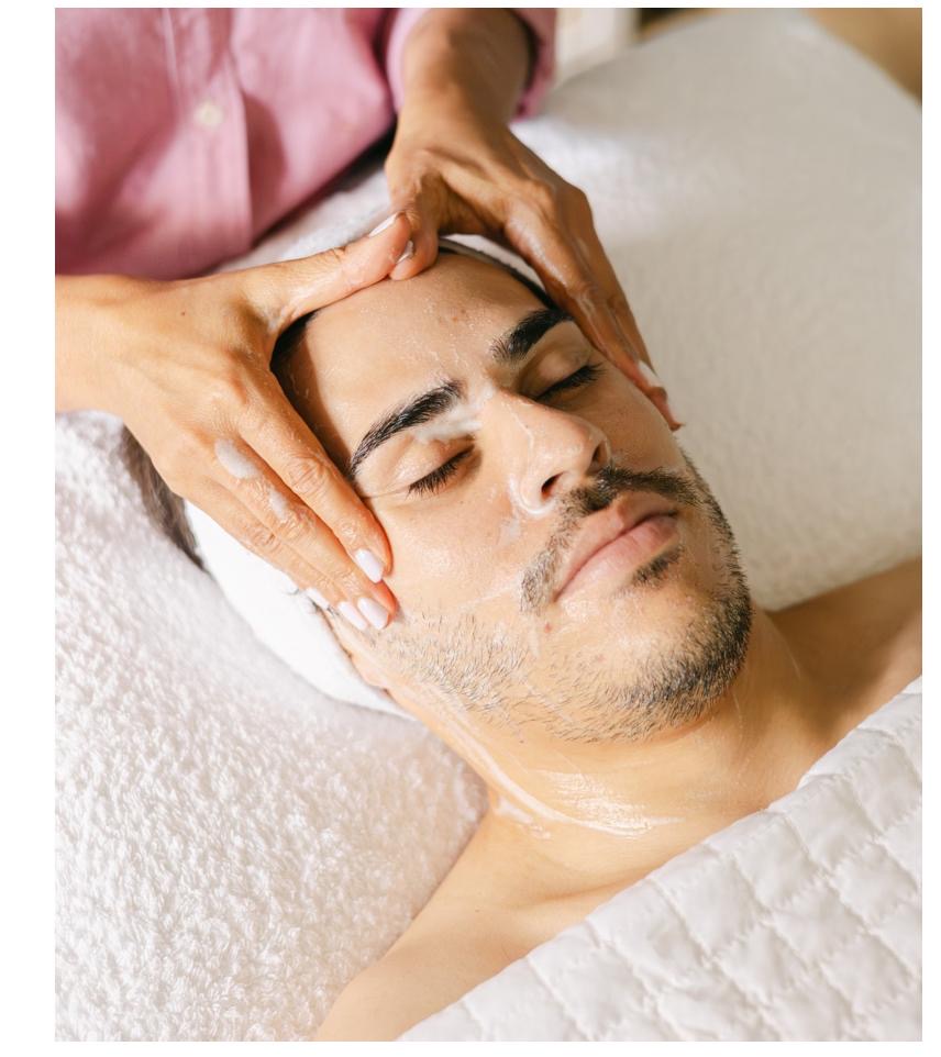 Close-up of a client’s face during a facial reflexology and acupressure treatment with therapist’s hands applying pressure points