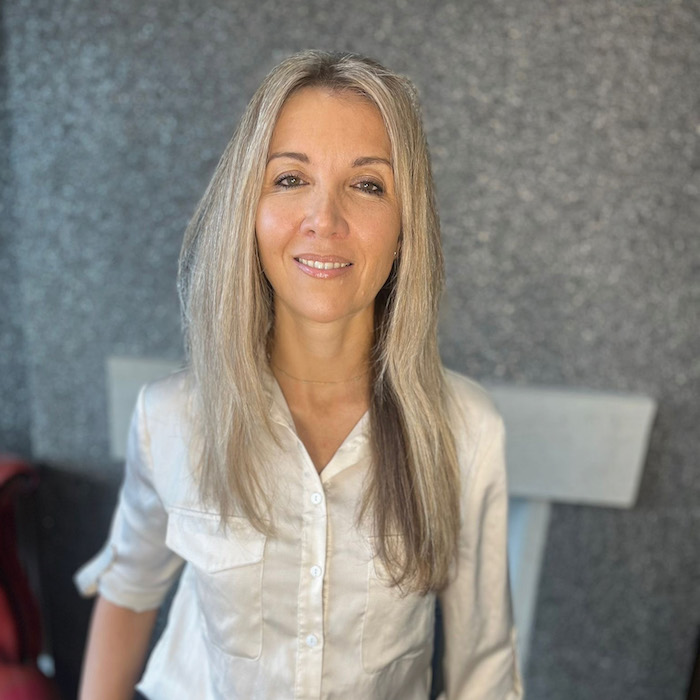 Headshot of Rachael Hyland, a middle aged blonde woman in a white shirt, smiling at the camera