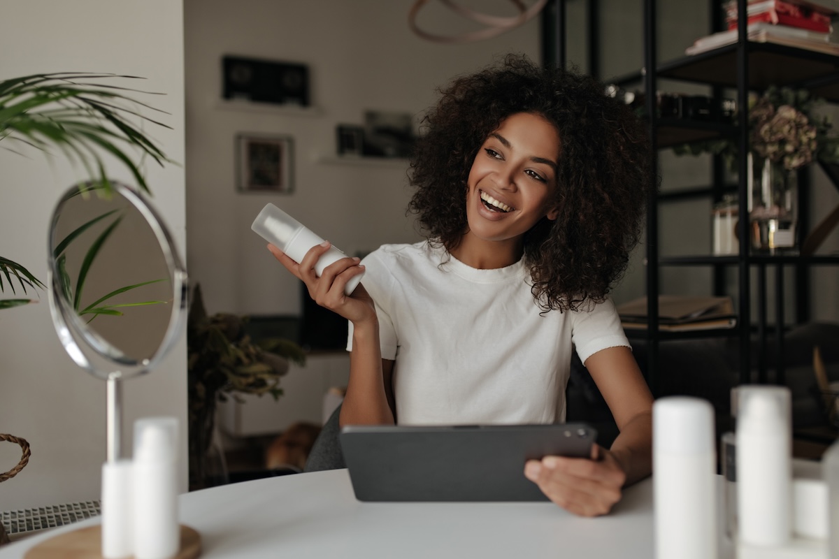 Salon owner holding a skincare product, demonstrating effective retail sales in a beauty clinic