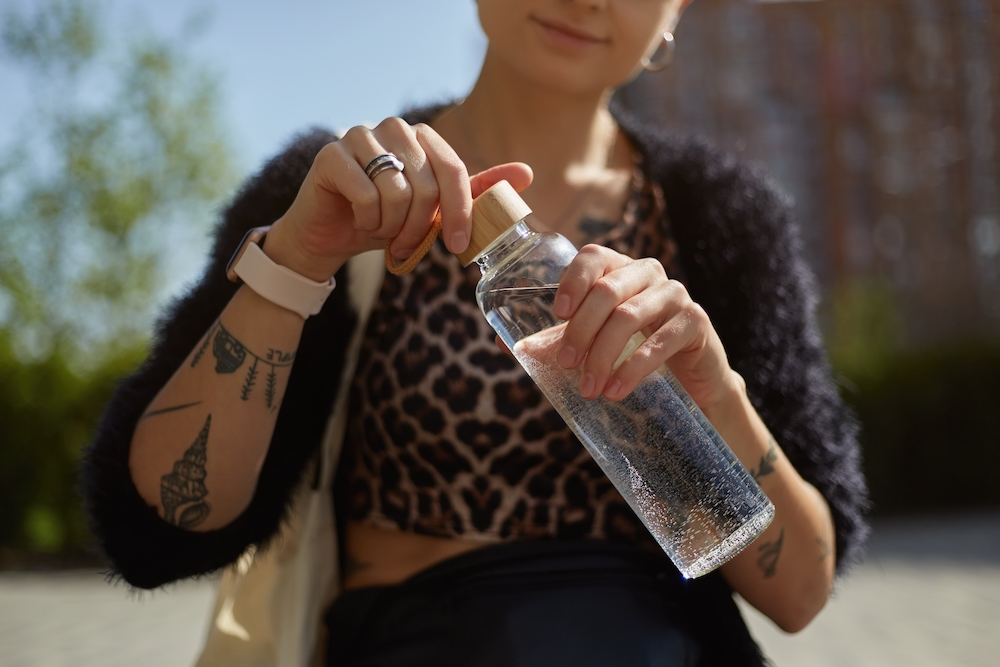 Woman using a reusable glass water bottle