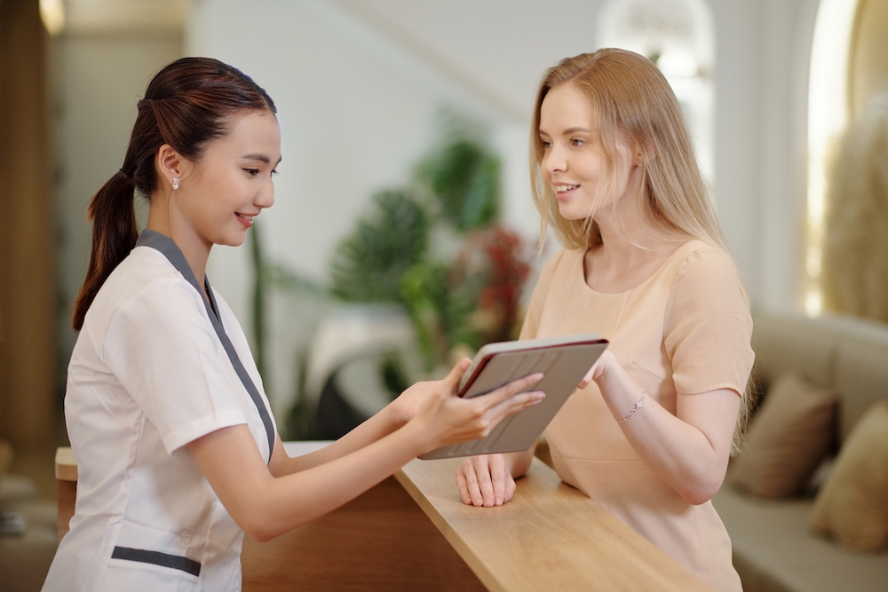 Salon employee calmly talking to client while holding a tablet device