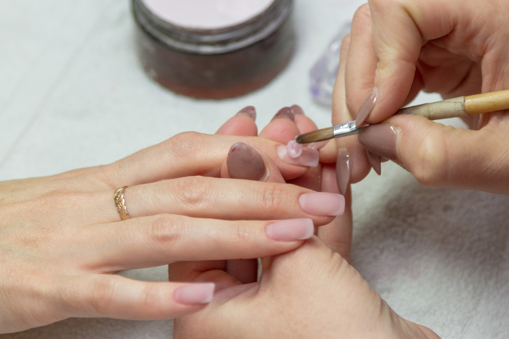 Nail tech demonstrating correct acrylic liquid-to-powder ratio