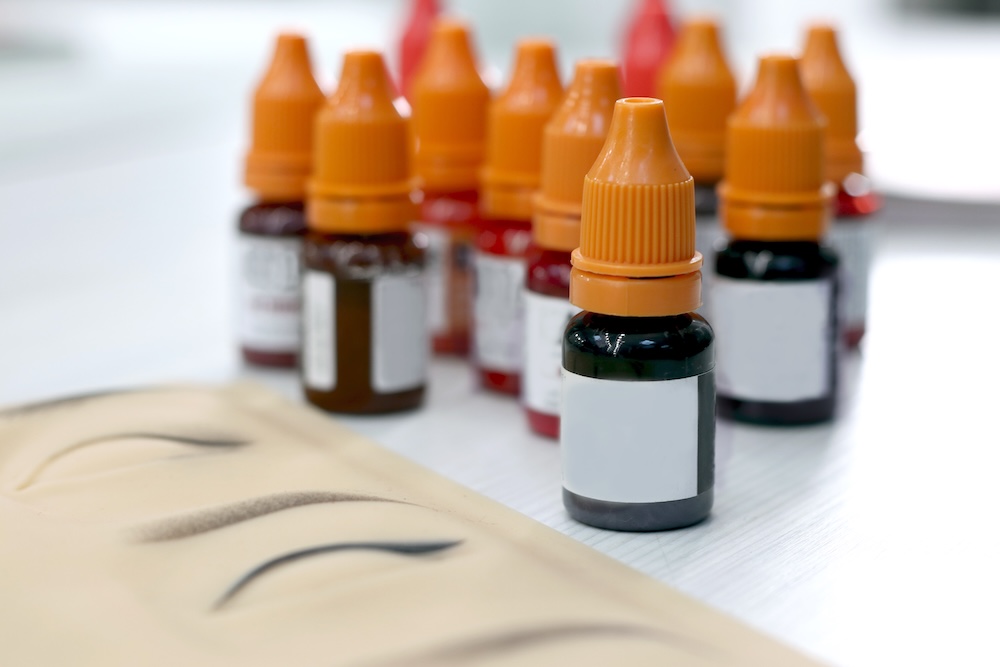 Bottles of eyebrow pigment and practice drawings of brows used by semi-permanent makeup artists for training and design