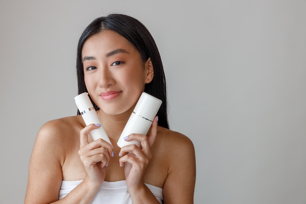 Woman in a white bath towel holding two different skincare products