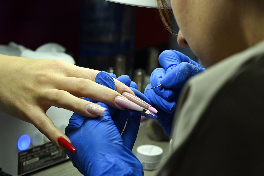 Close-up of nail tech painting long nails