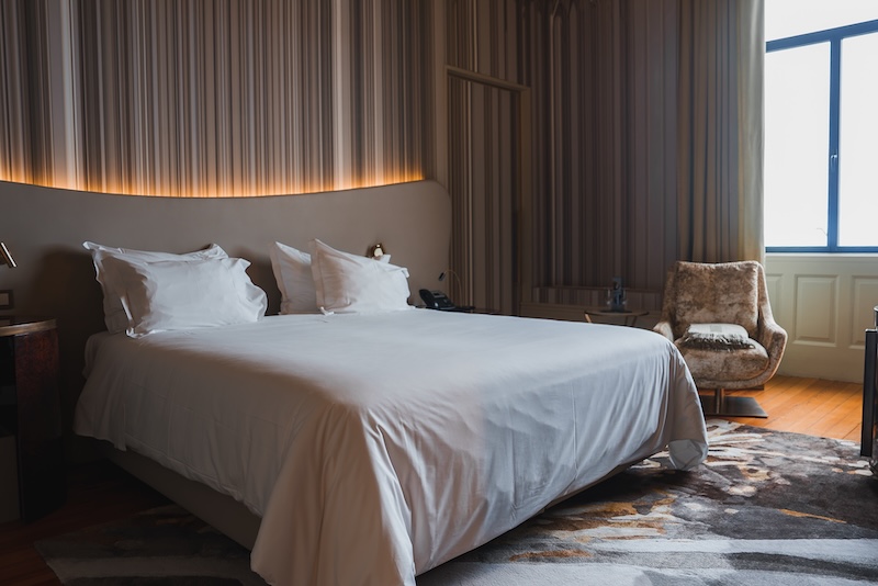 Spacious hotel bedroom designed for restful sleep with ambient lighting, crisp white linens, and wellness-focused décor