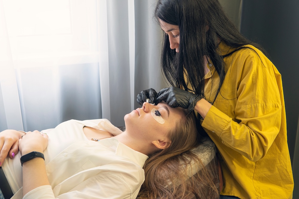 Beauty therapist applying lash tint to a client during a professional salon treatment