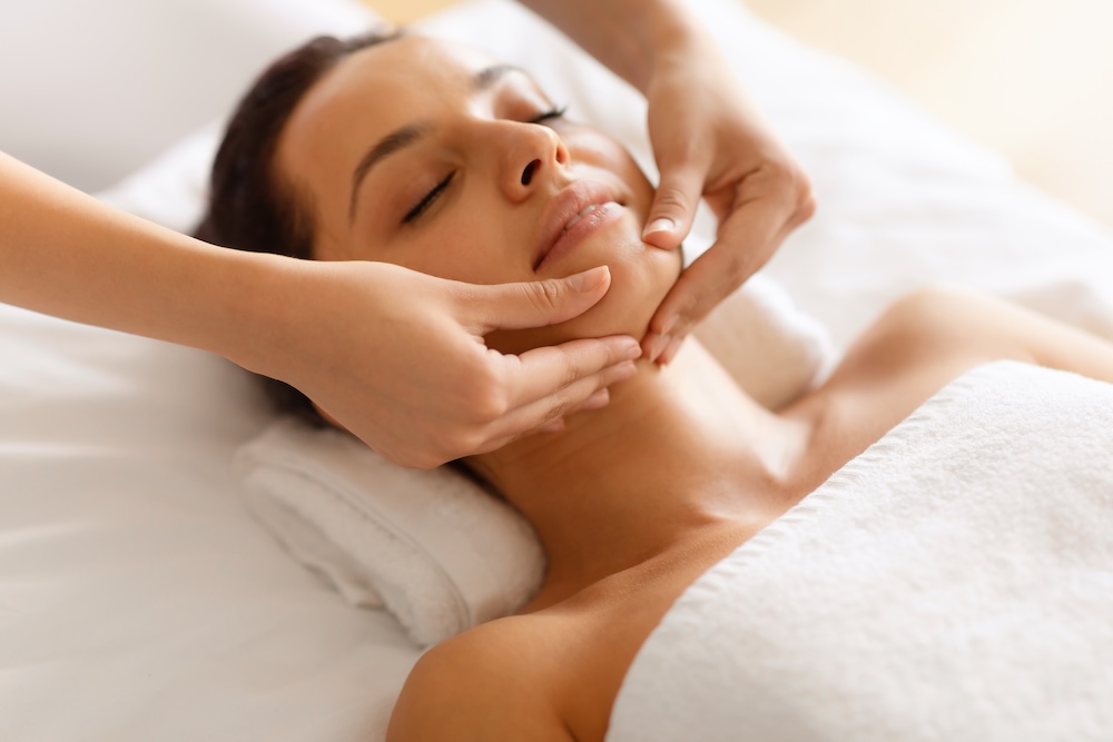 Beauty therapist performing a facial massage on a client to improve circulation and skin health in a spa setting