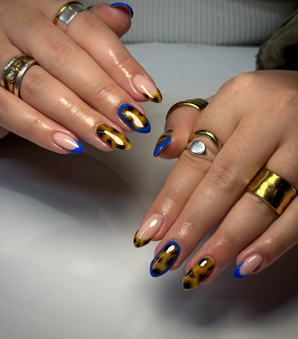 Brown tortoiseshell nails with cobalt blue outlines and French tips