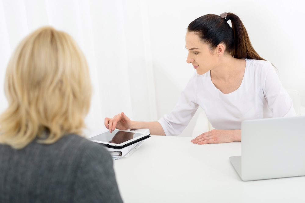 A beauty therapist reviewing consultation notes with a client before starting a treatment