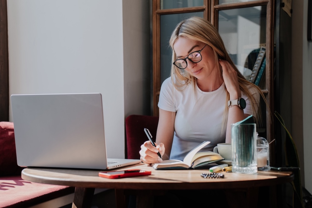 Journalist writing a beauty PR story on a laptop with a notepad beside them