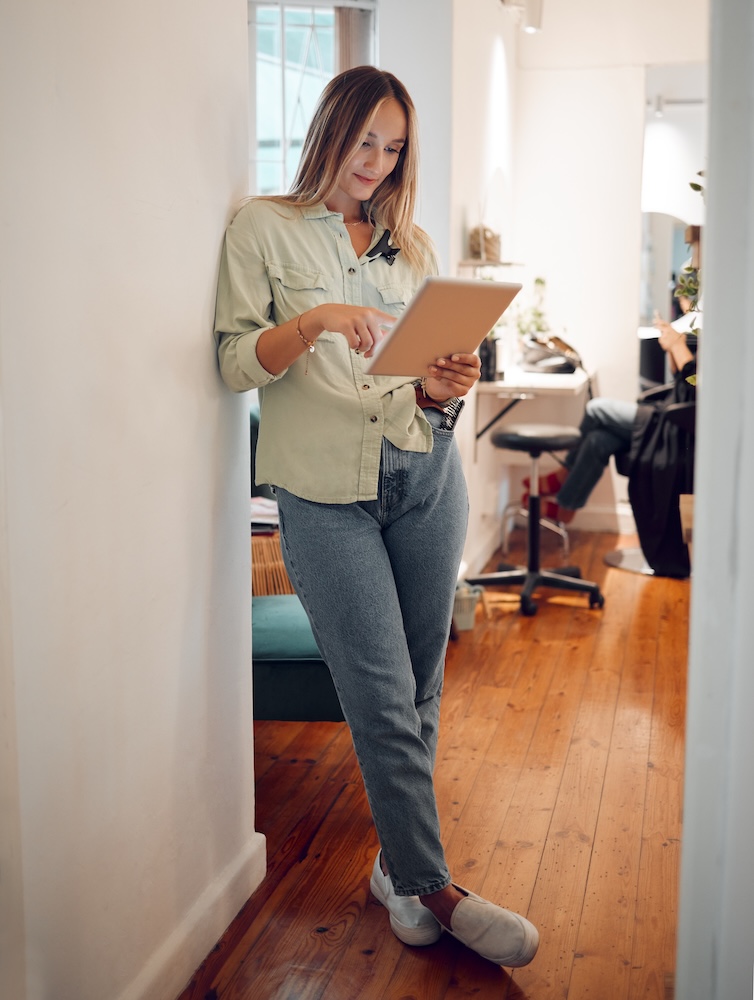 Beauty salon owner checking her schedule on a digital tablet, managing online appointments and bookings for her small business