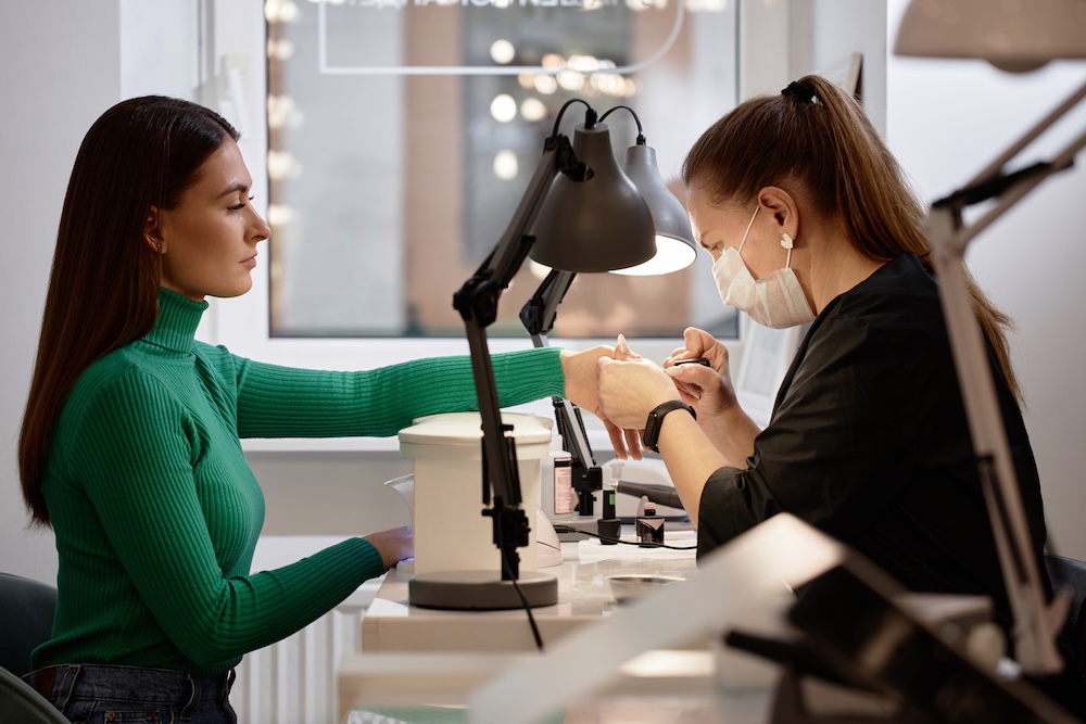 Nail technician examining a client’s nails before a Japanese manicure treatment
