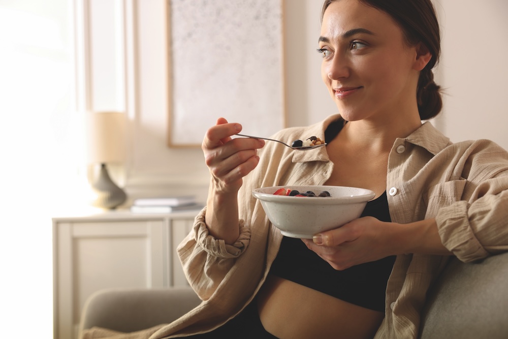 Woman eating a fruit and granola bowl to represent fibre-rich nutrition and gut health