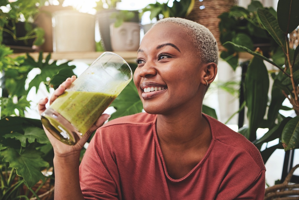 Woman drinking a green smoothie as part of gut-friendly, skin-supporting nutrition trends