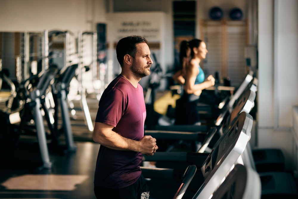 Man running on a treadmill in a gym to maintain fitness and support men’s wellbeing