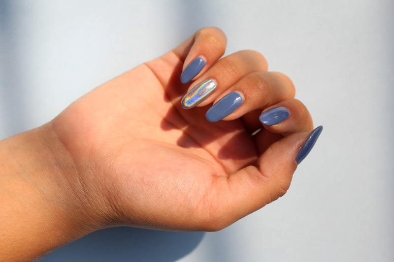 Blue gel nails with iridescent chrome accent on one finger, glossy reflective manicure