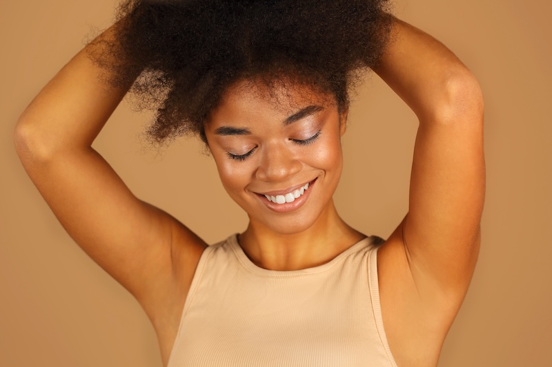 A woman of colour showing smooth, hair-free underarms after laser hair removal
