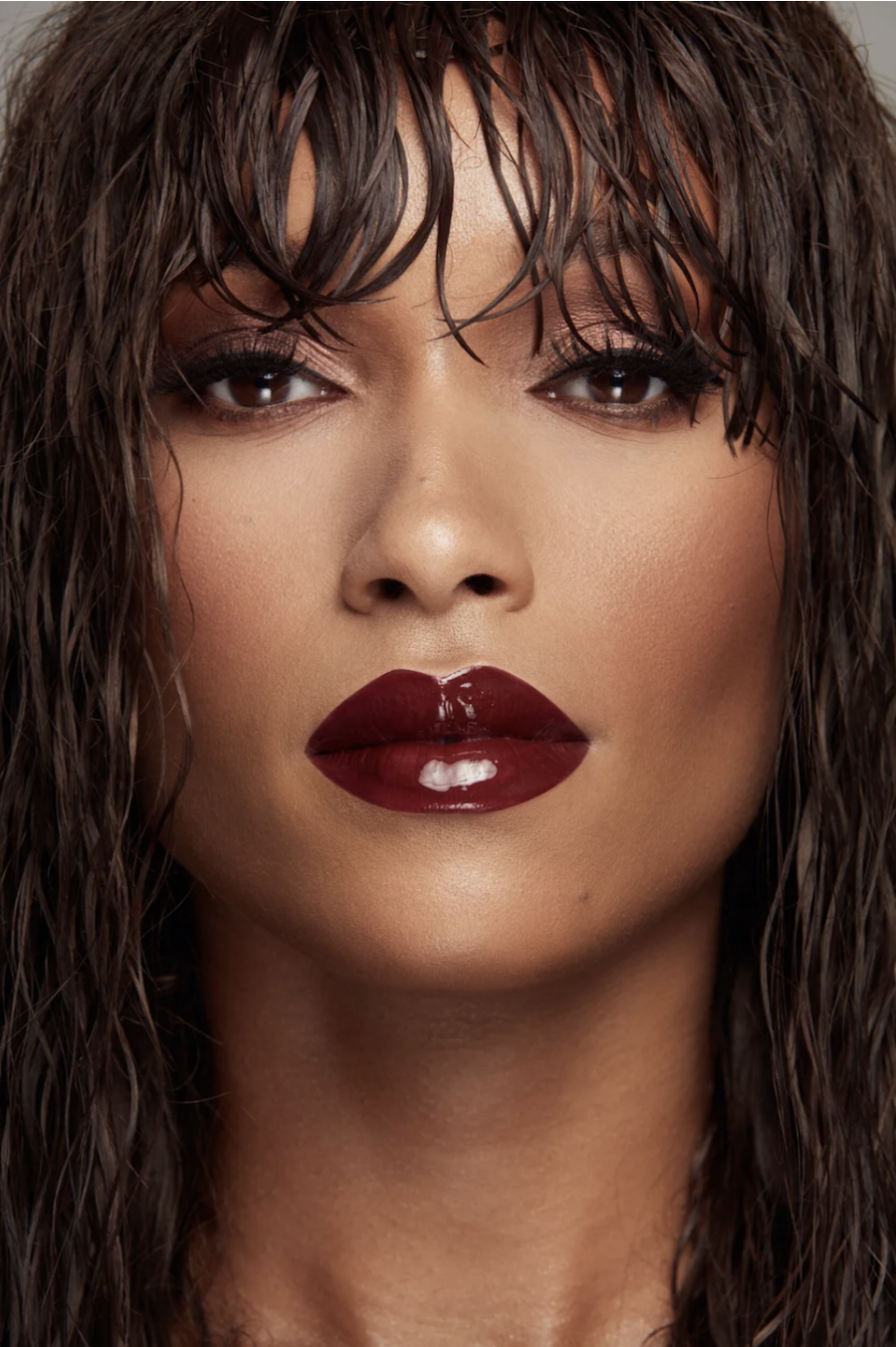 Woman with wet-look hair with warm blush and a glossy dark lip