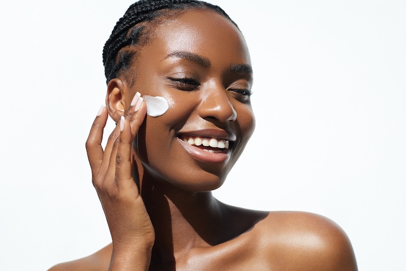 Woman applying astaxanthin face cream to her skin, demonstrating topical antioxidant skincare use