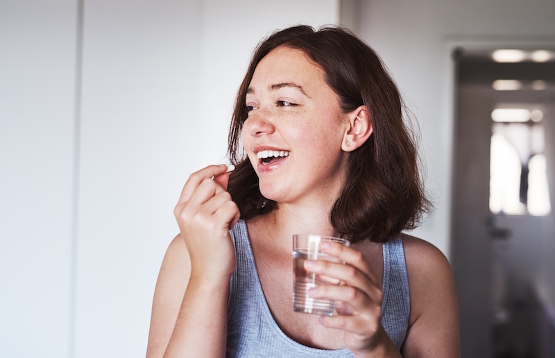Woman taking a supplement reflecting beauty-from-within and precision nutrition trends