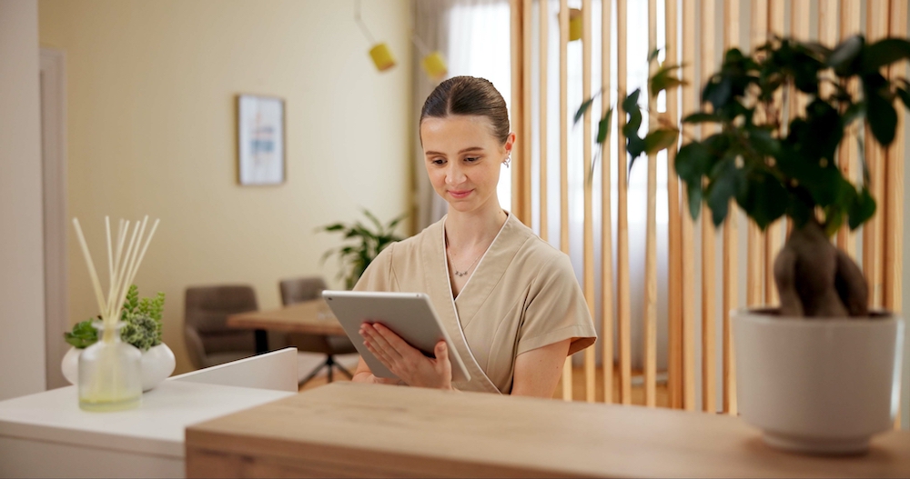 Happy receptionist at spa/clinic on tablet behind desk