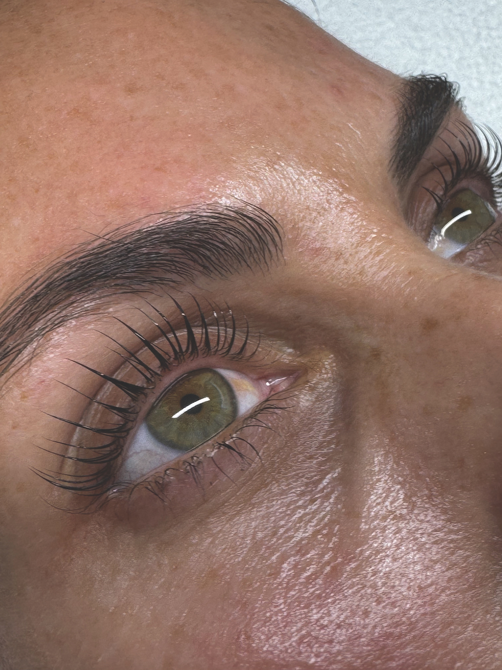 Close up image showcasing results of a Korean lash lift; lashes are long, curled, glossy and black