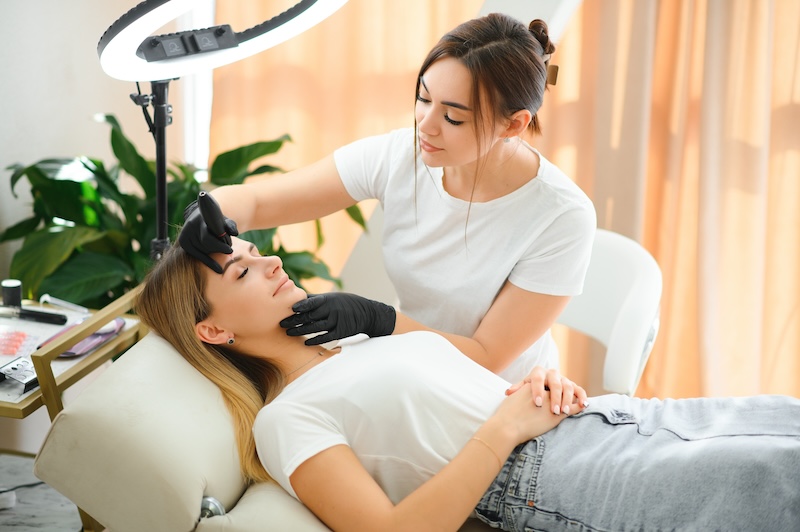 Client receiving a facial treatment in a UK beauty salon while a therapist assesses her skin