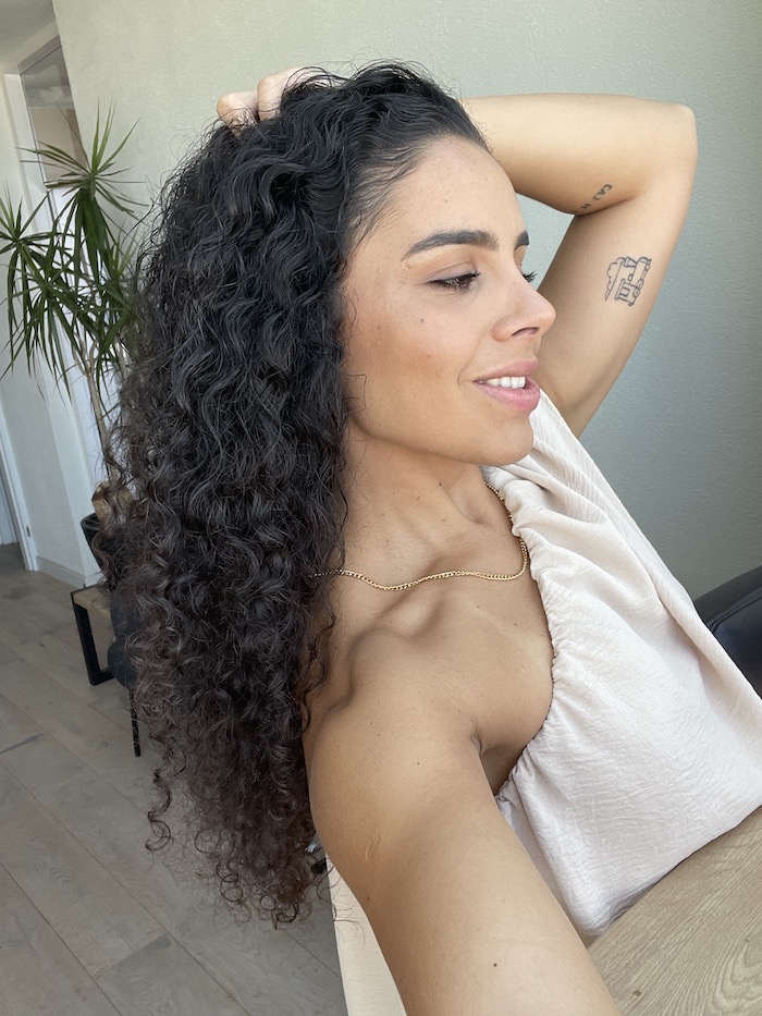 Woman with curly dark hair, with volume and hair extensions