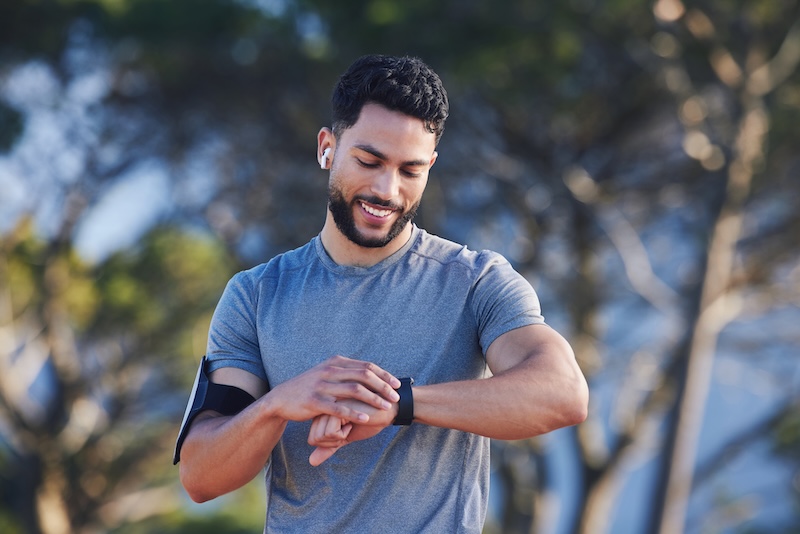 Man checking data on a fitness watch, highlighting the rise of wearable technology and biohacking in luxury wellness