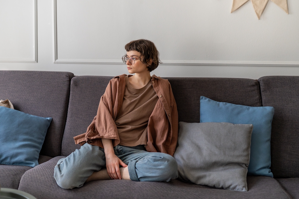 Young person of apprentice age, sitting at home on a sofa