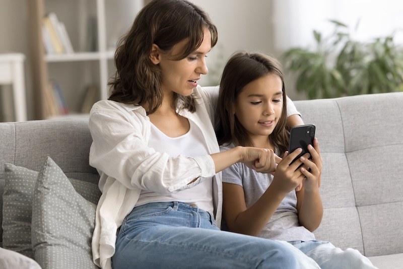 Mother and pre-teen daughter looking at social media together on a smartphone