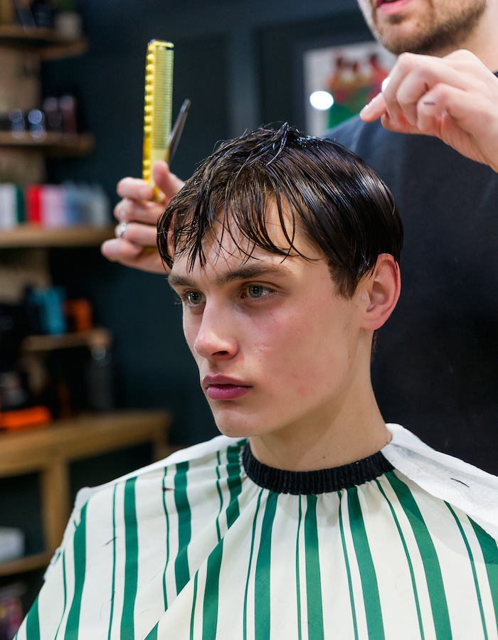 Male client sitting in a barbershop having his fringe cut