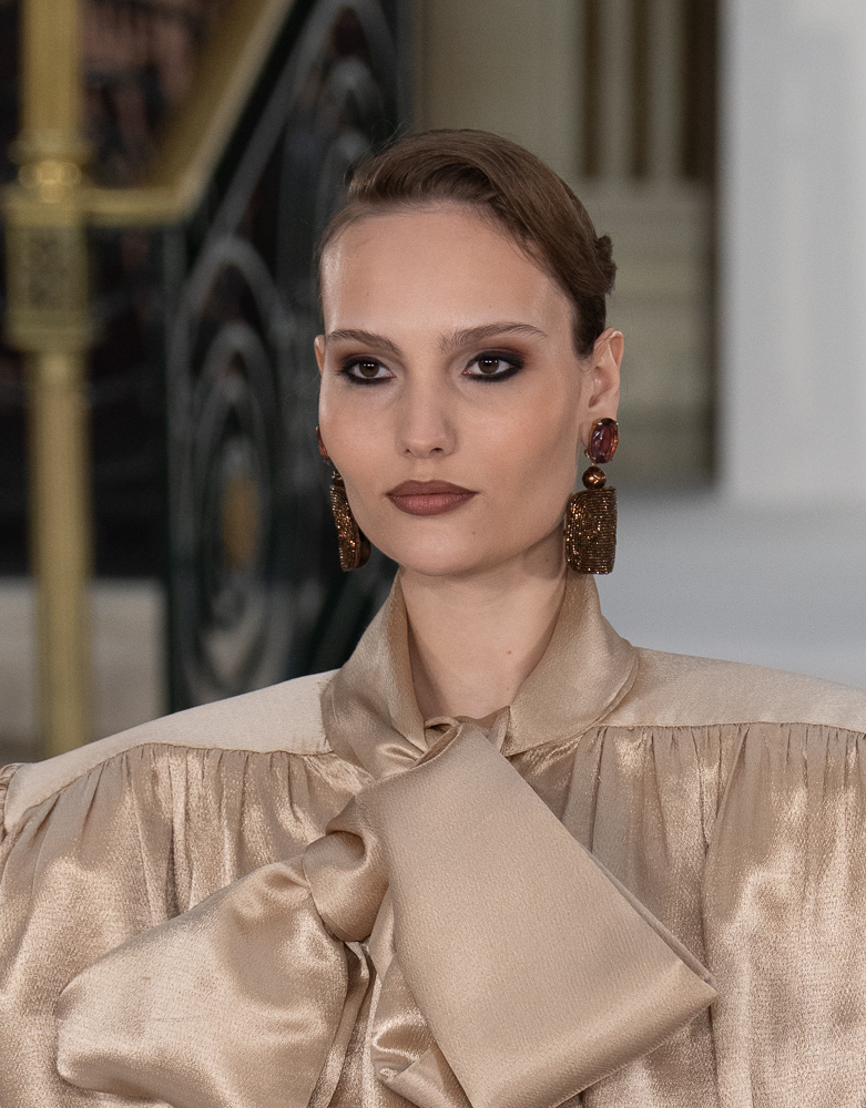 Model with black eyeliner and minimal fluffy brows, walking for Paul Costelloe at LFW