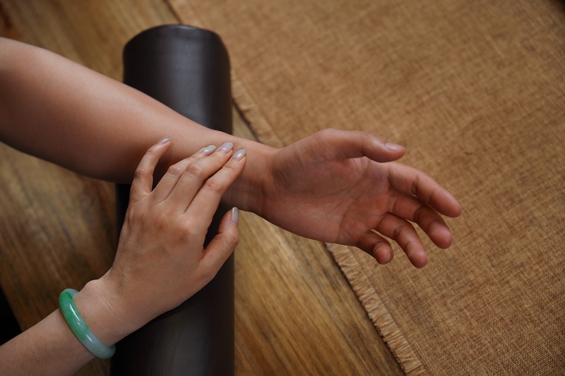 Client receiving a Traditional Chinese Medicine acupressure massage on the wrist in a wellness clinic