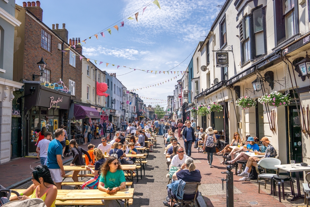 Image of Brighton Laines high street looking busy, with people sitting around on tables and people walking past