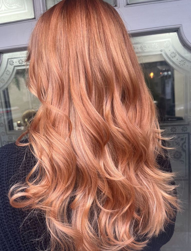 Back of a woman's head, light copper hair styled in loose waves