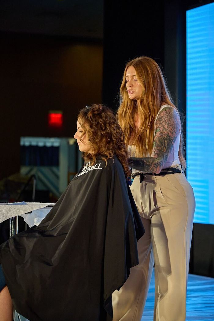 Hairdressers Lisa Giles doing a model's hair on stage as part of live education