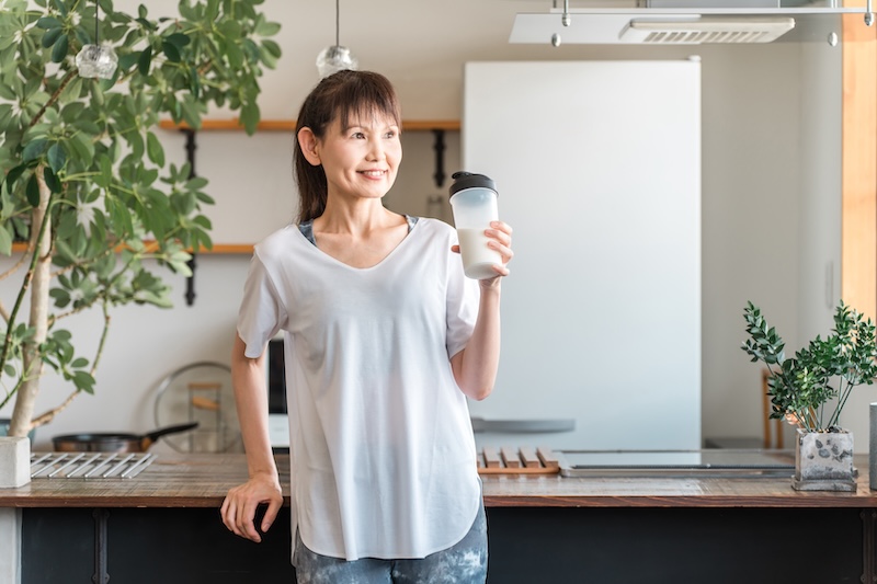 Mature woman holding a drink with a creatine supplement, supporting energy, muscle tone, and healthy ageing