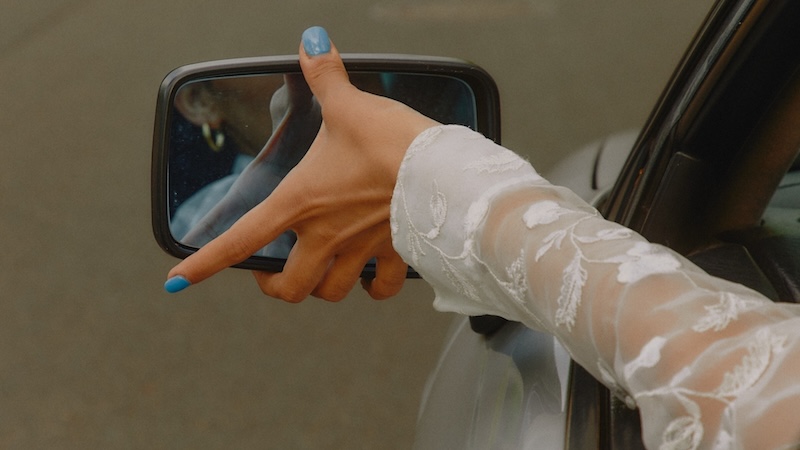 Close-up of bride’s hand with blue nail polish and lace sleeve, highlighting 2026 wedding nail trends
