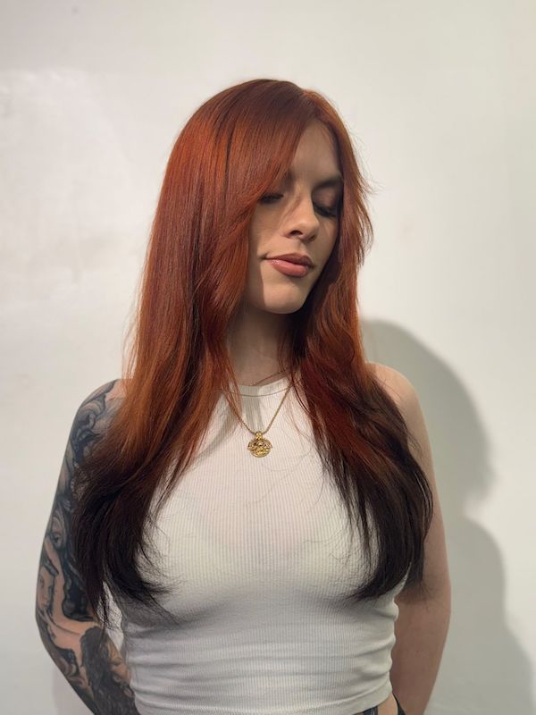 A woman with long copper hair with black "fox tail" ends