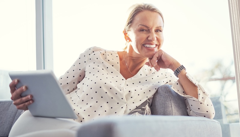 Salon owner smiling while using a tablet to manage digital marketing, SEO and online bookings for a beauty business.