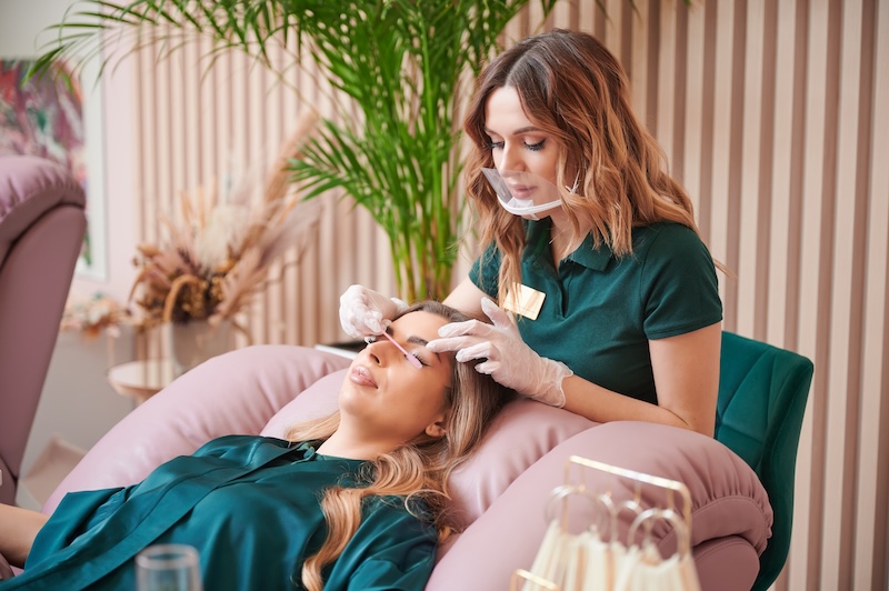 Lash technician performing an eyelash extension treatment on a client in a beauty salon, representing searchable beauty services and local salon SEO.