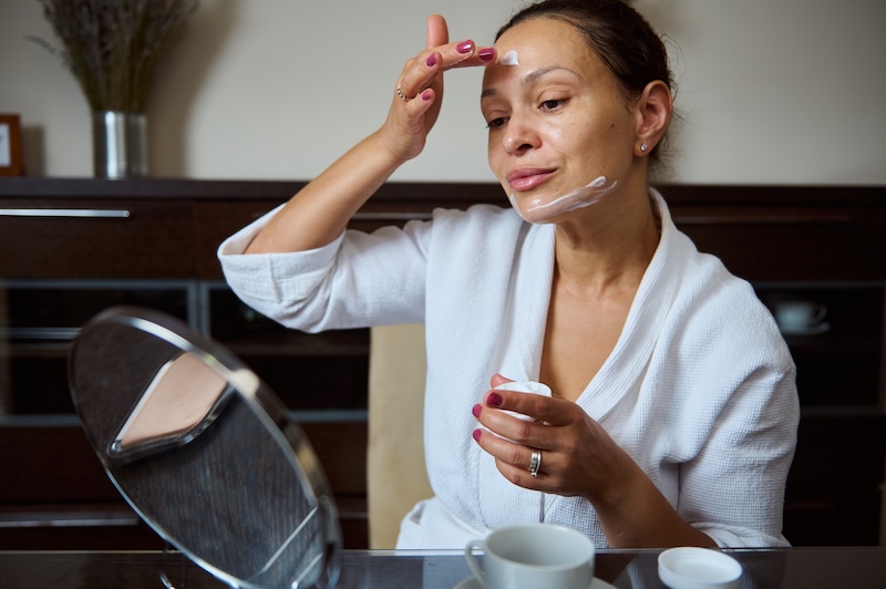 Woman applying skincare to her face at home as part of her daily homecare routine