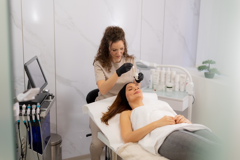 Skin therapist performing a facial treatment on a client in a clinic setting