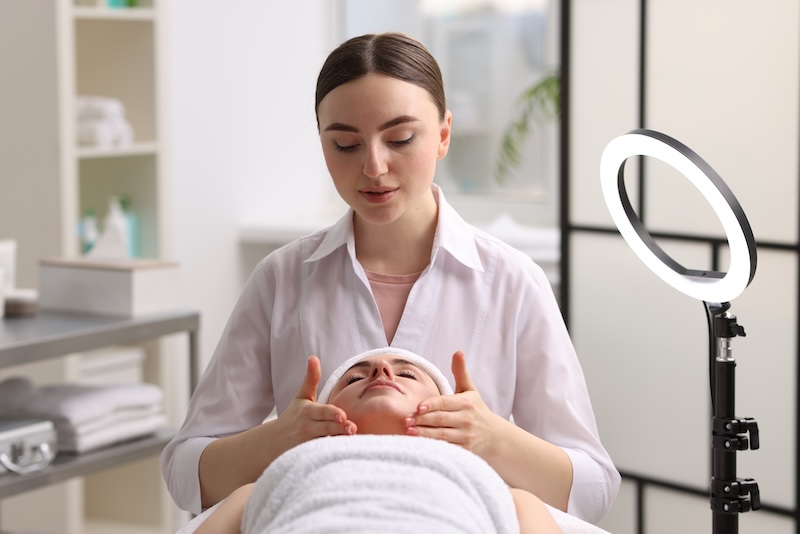 Facialist carrying out a professional facial treatment on a client at a beauty salon.